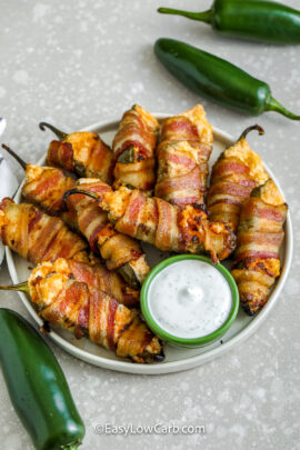 bacon wrapped jalapenos on a plate with dip