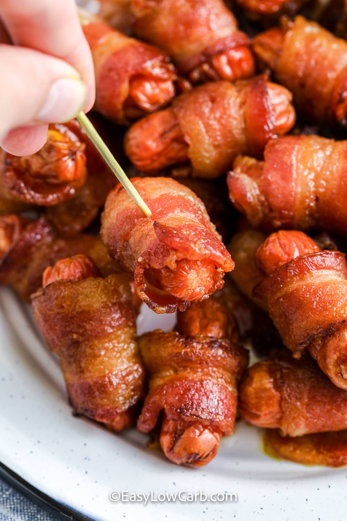 bacon wrapped little smokies in a dish with one being picked up with a toothpick
