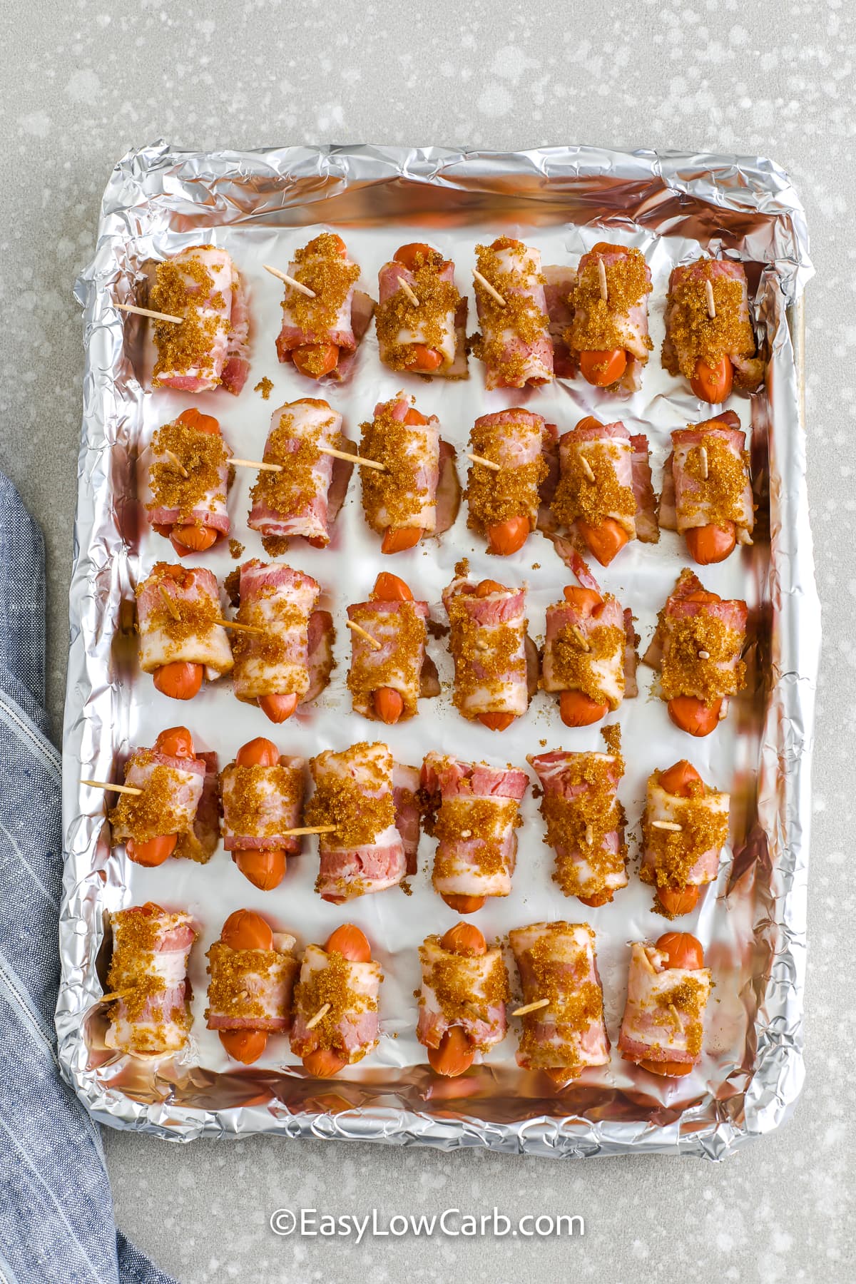 bacon wrapped little smokies on a baking sheet before being baked