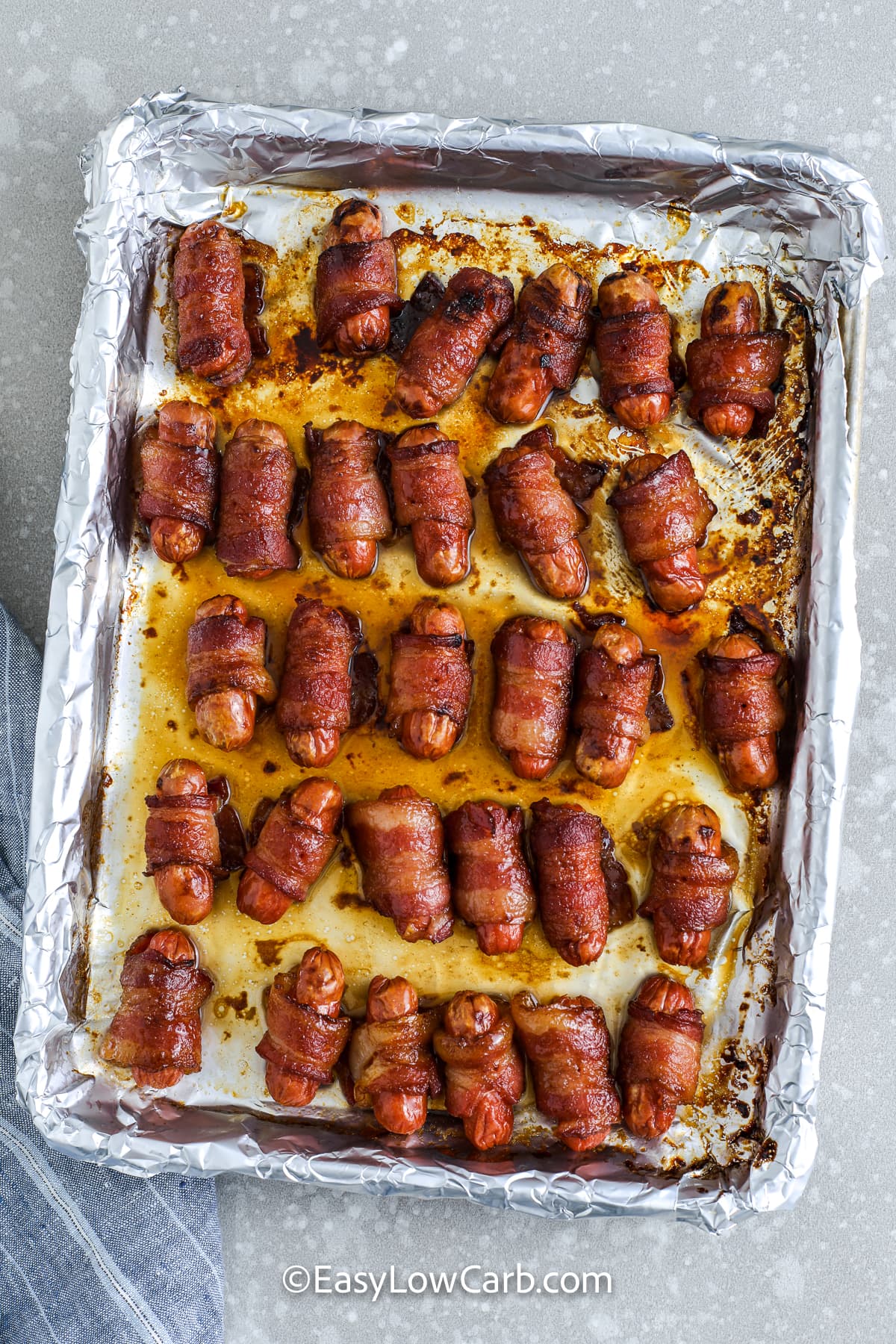 bacon wrapped little smokies on a baking sheet with foil
