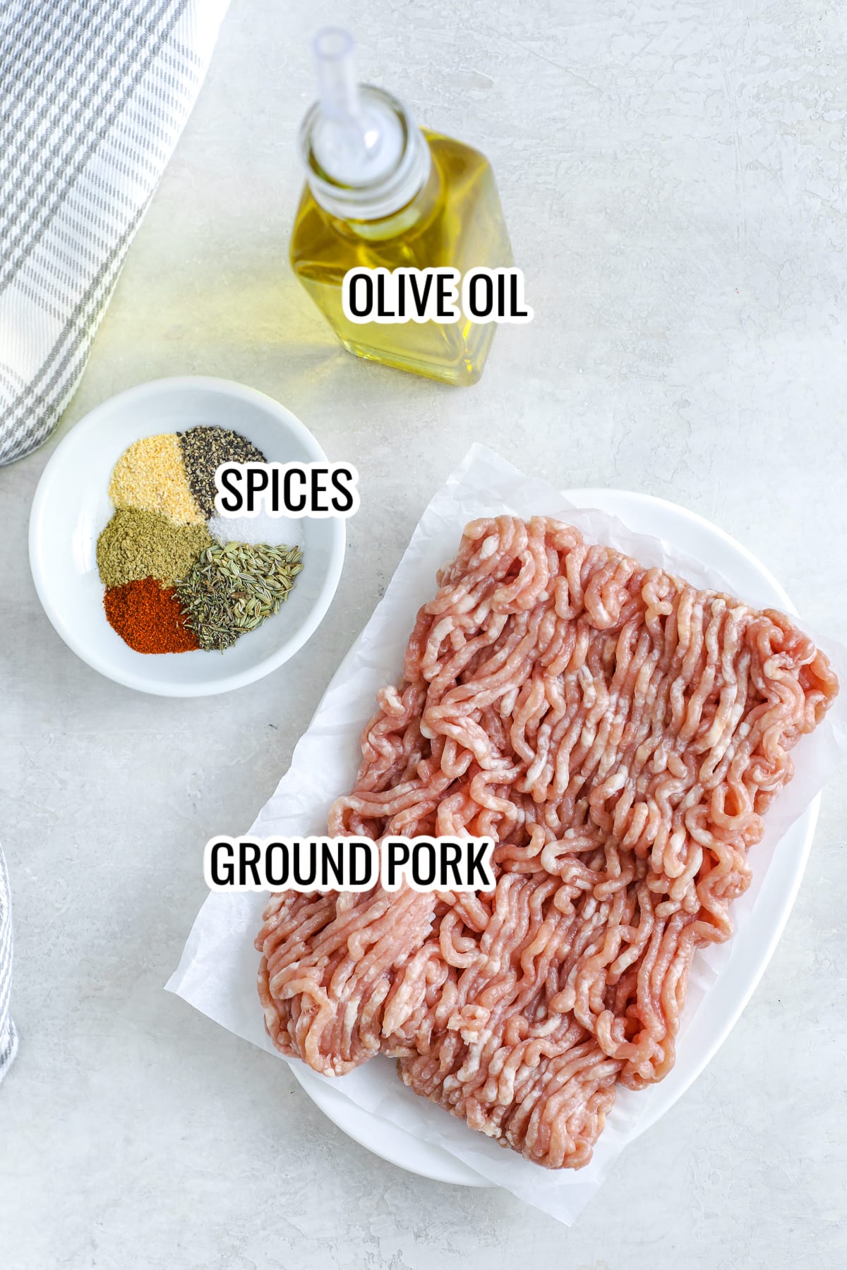 ingredients assembled to make breakfast sausage patties, including ground pork, spices, and olive oil
