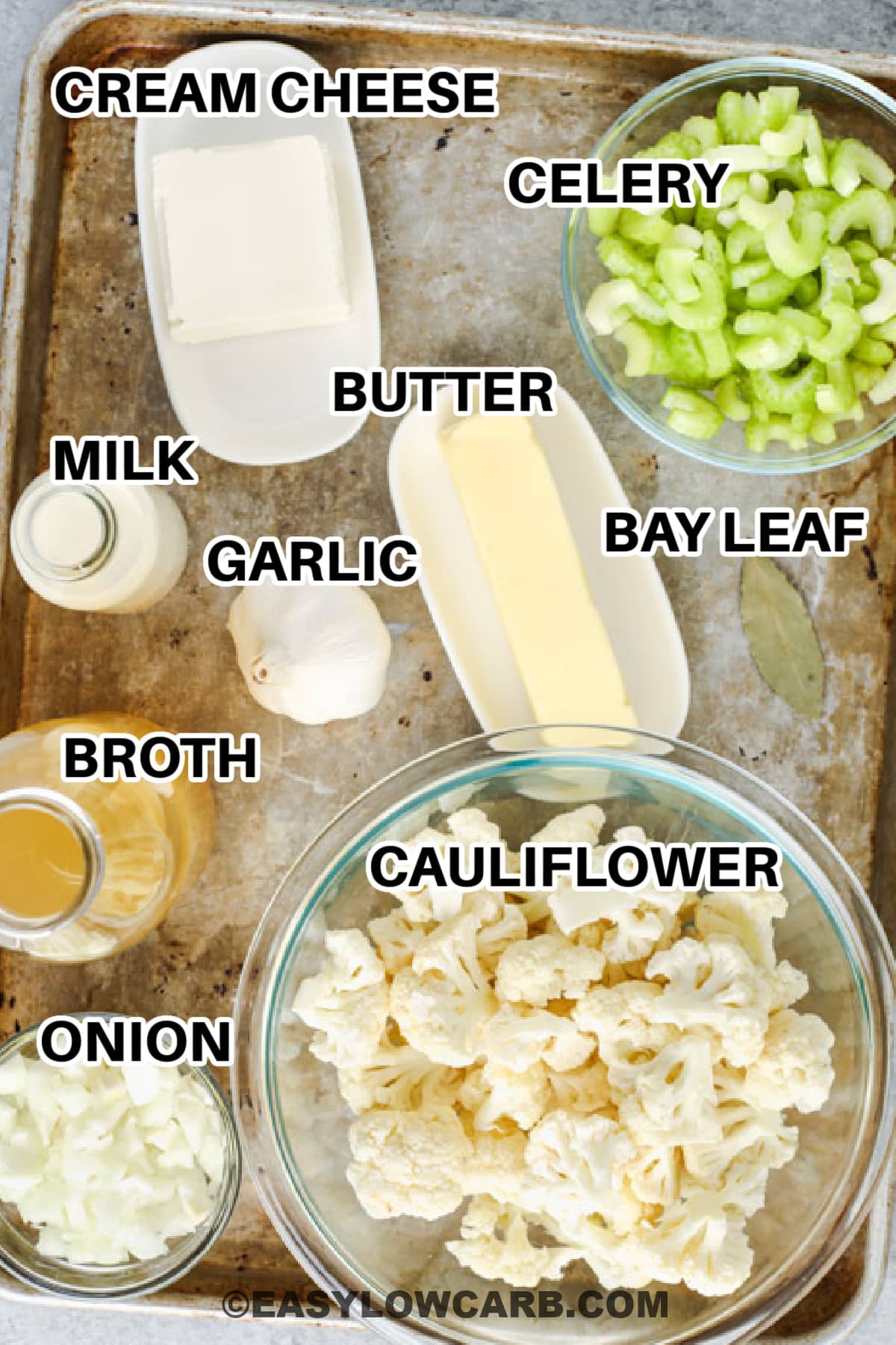 creamy cauliflower soup ingredients including cream cheese, celery, butter, milk, garlic, bay leaf, broth, cauliflower, and onion