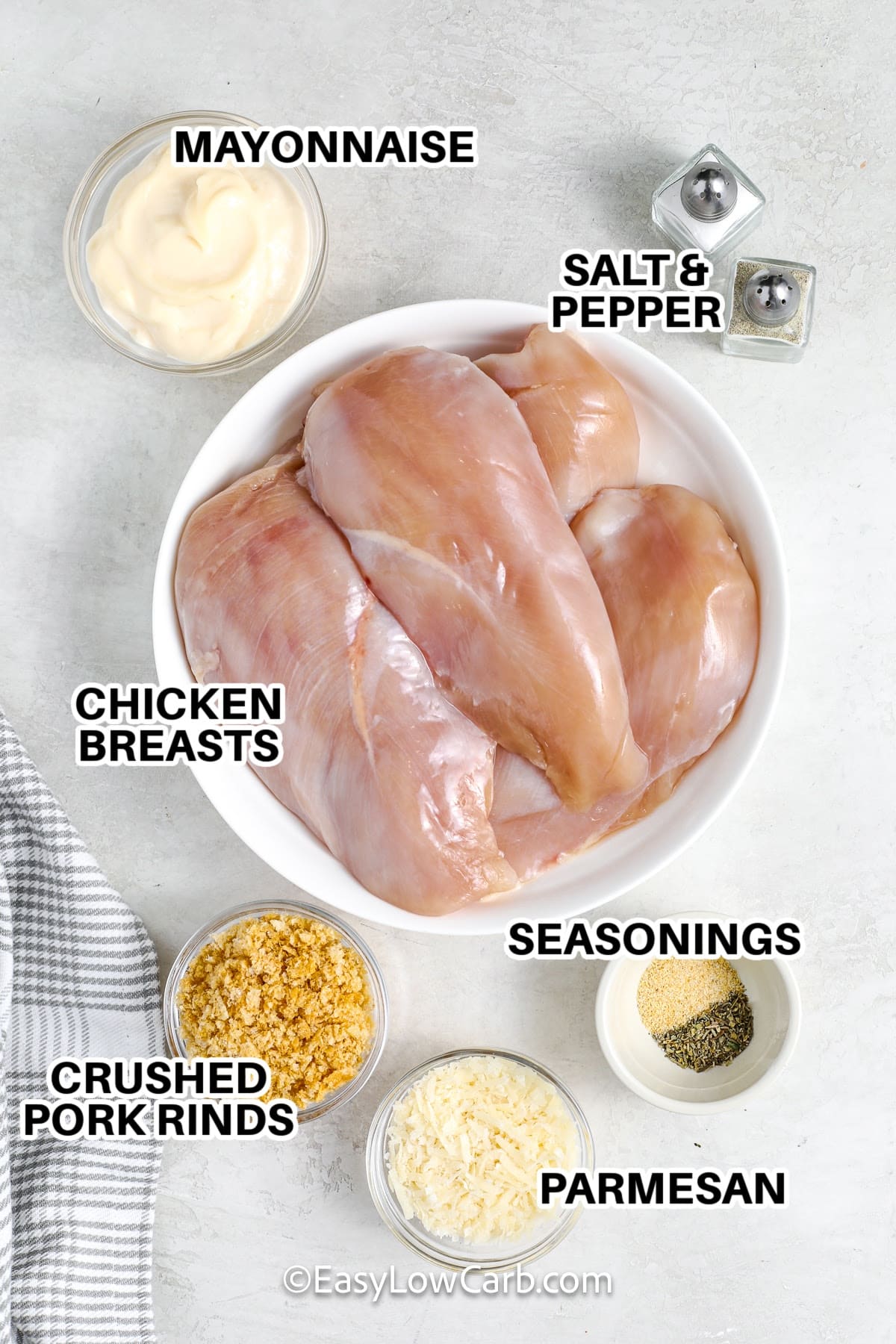 Ingredients to make Baked Parmesan Chicken labeled: Mayonnaise, Salt & Pepper, Chicken Breasts, Seasonings, Crushed Pork Rinds, Seasonings, and Parmesan.