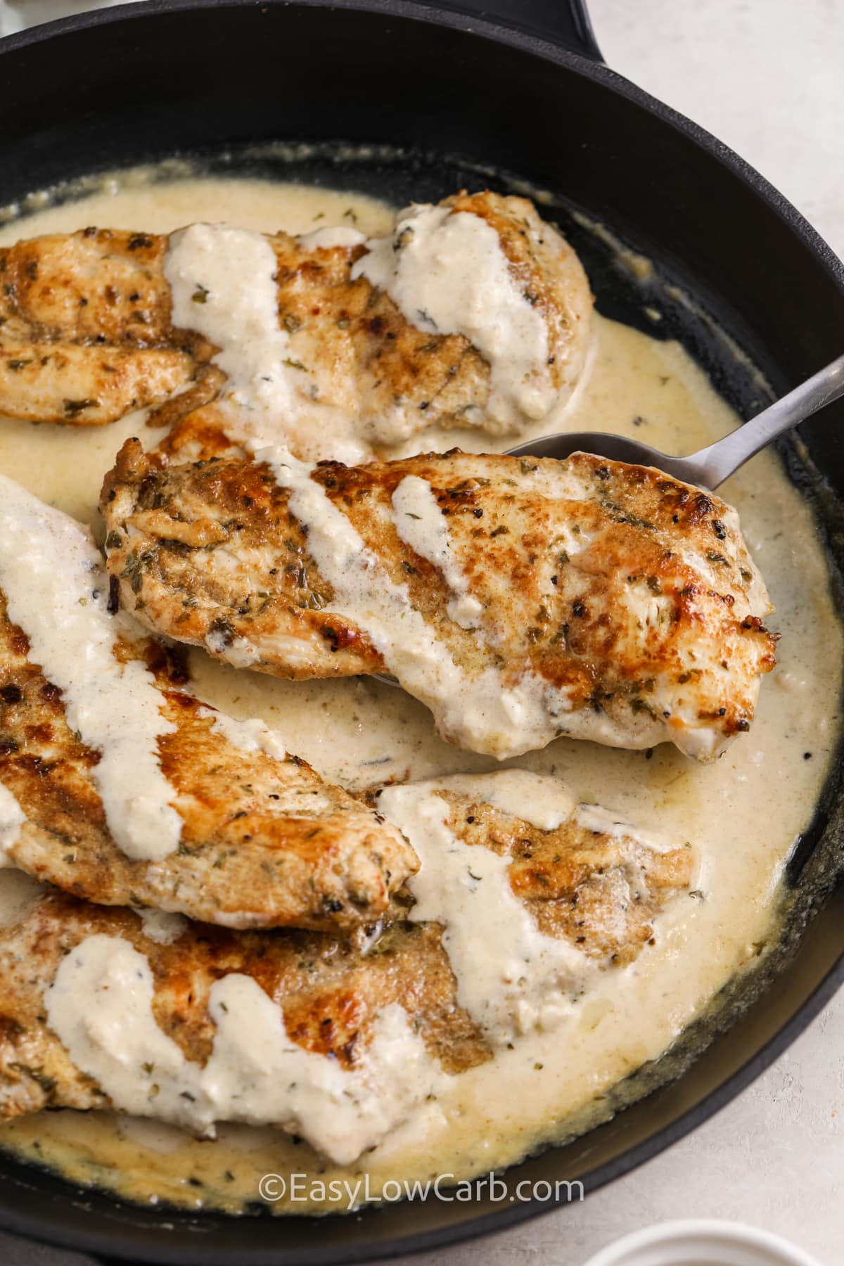 cream cajun chicken being spooned out of a skillet