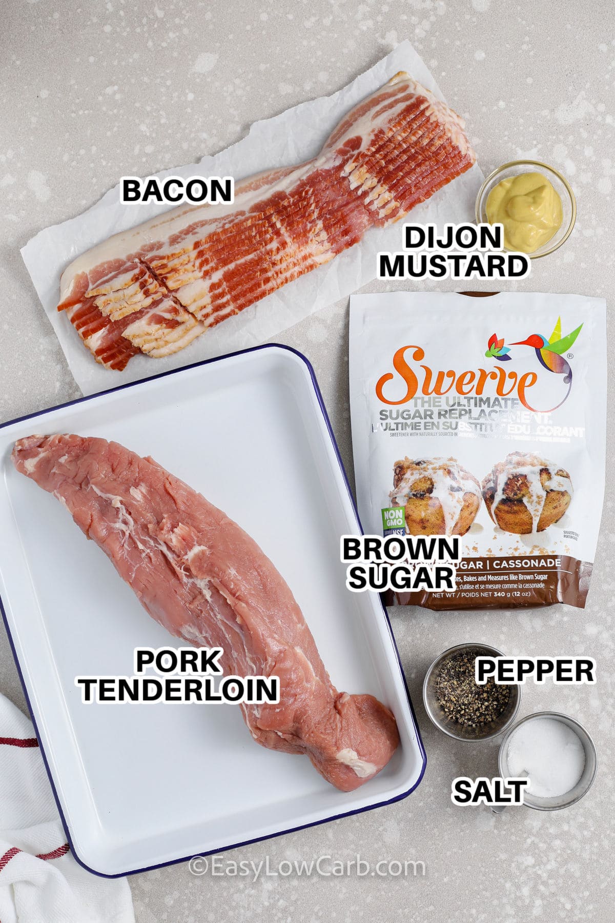 Ingredients to make Bacon Wrapped Pork Tenderloin labelled: bacon, dijon mustard, brown sugar, pepper, salt and pork tenderloin.