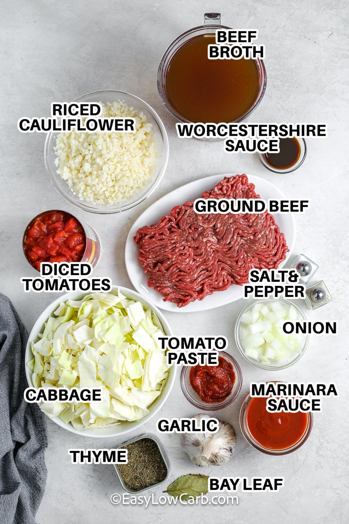 Ingredients to make cabbage roll soup labeled:beef broth, worcestershire sauce, riced cauliflower, ground beef, salt & pepper, diced tomatoes, cabbage, tomato paste, onion, marinara sauce, garlic, thyme, bay leaf
