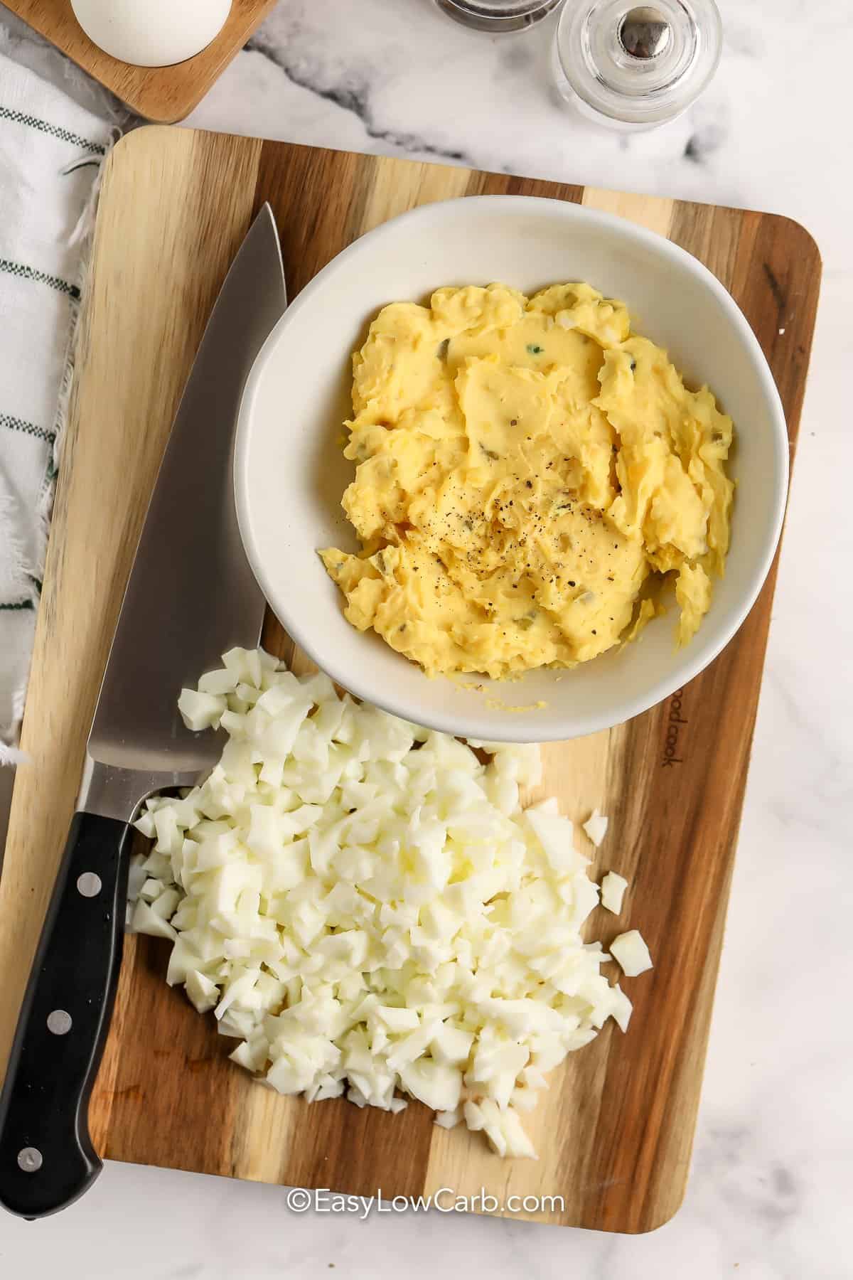 process to make Keto Egg Salad - egg yolks mixed up and egg whited chopped on a wooden board