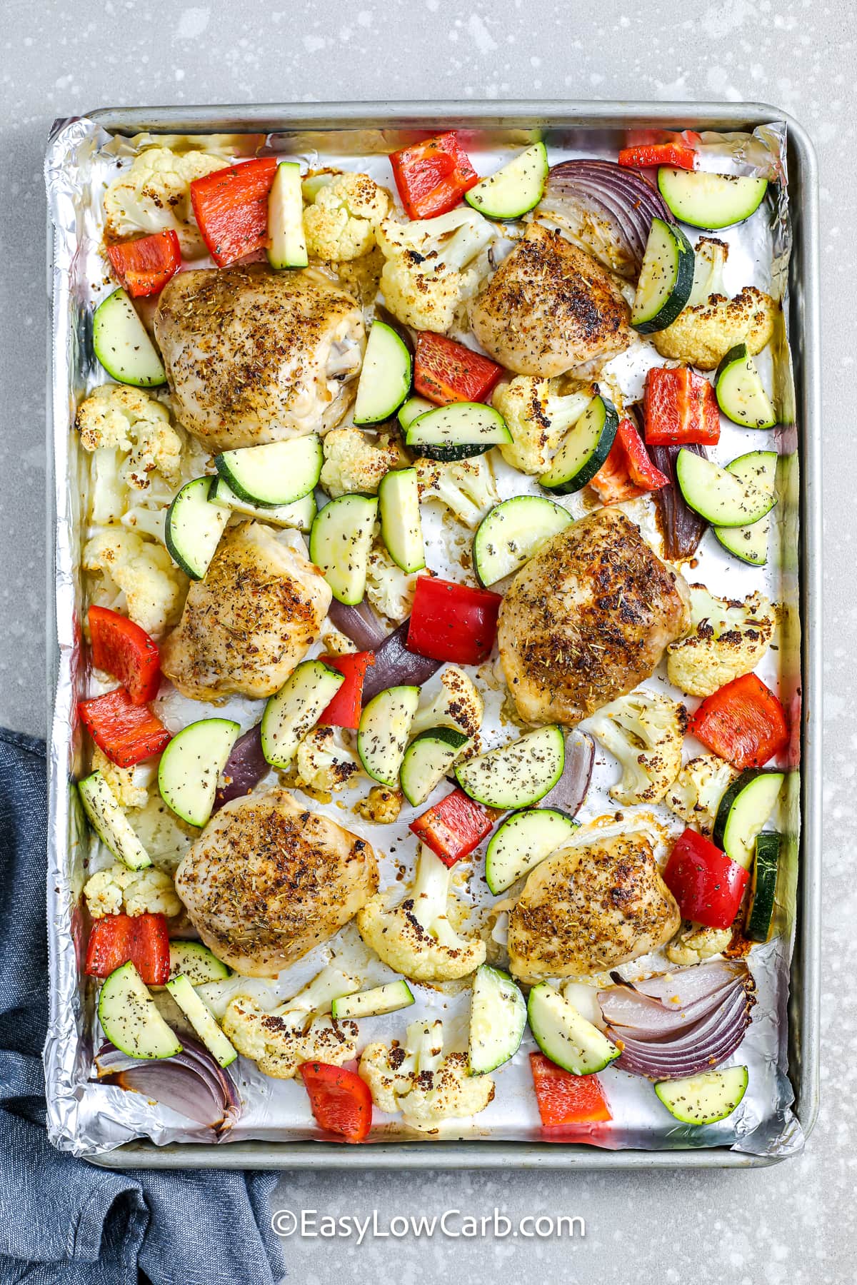 partially cooked sheet pan chicken and veggies on a pan