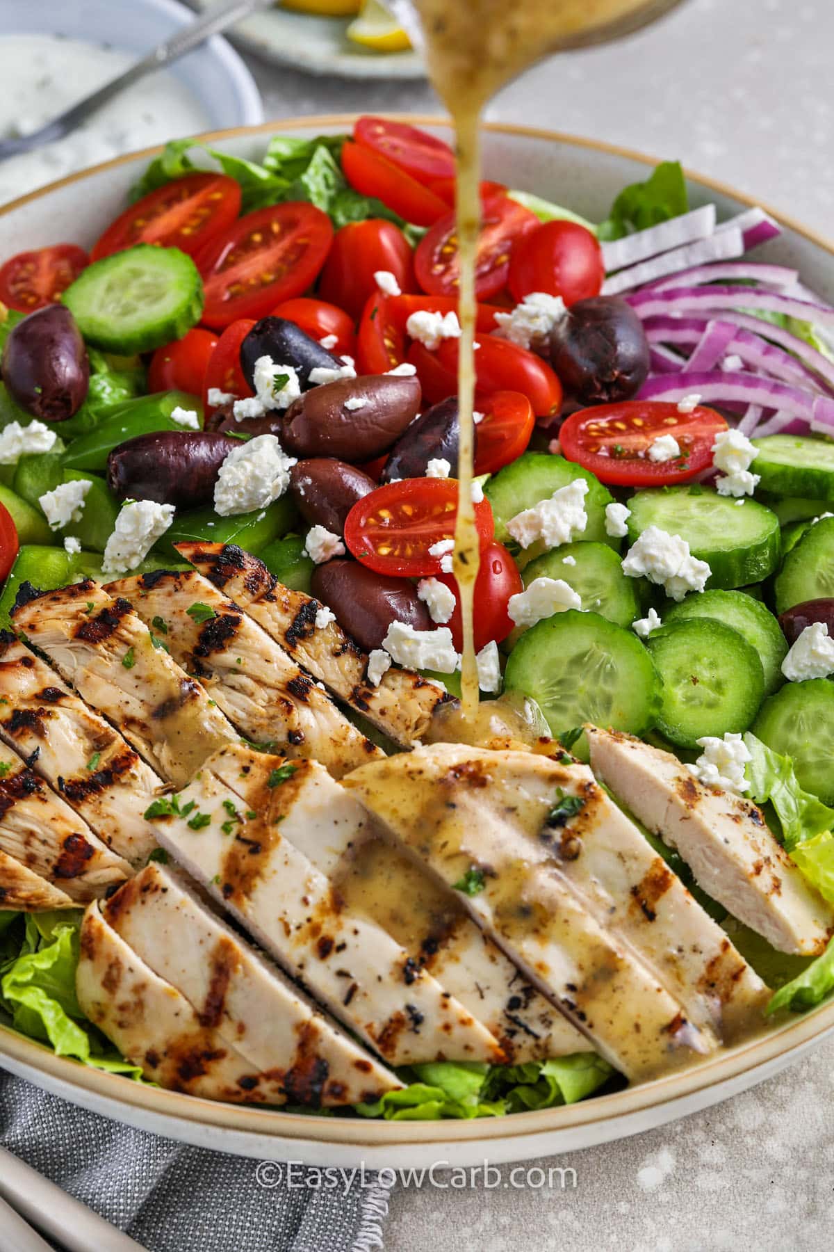 adding dressing to ingredients to make Greek Chicken Salad