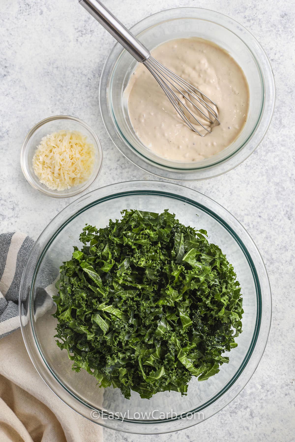kale , parmesan and dressing in bowls to make Kale Caesar Salad