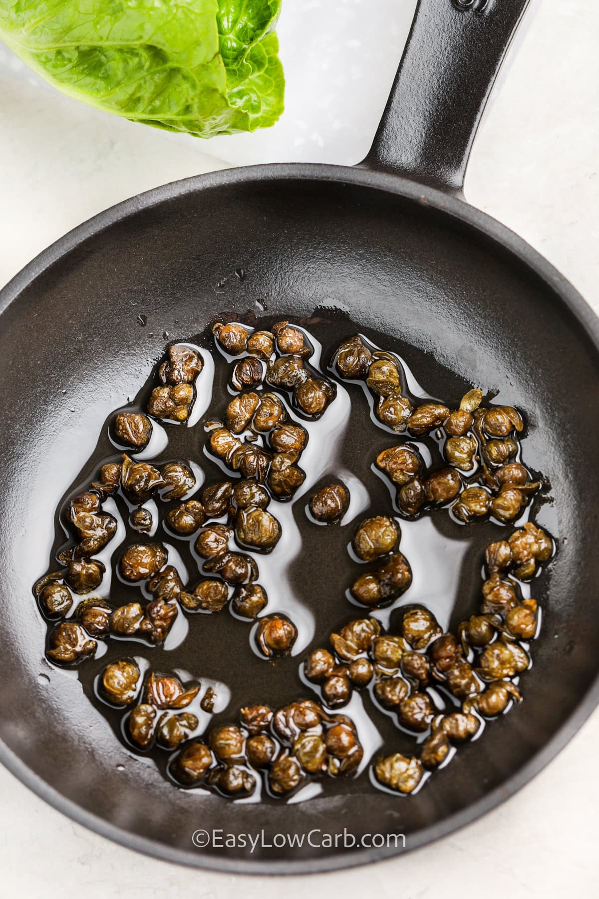 Capers and oil in a frying pan