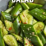 Smashed cucumber salad prepared in a bowl with a title