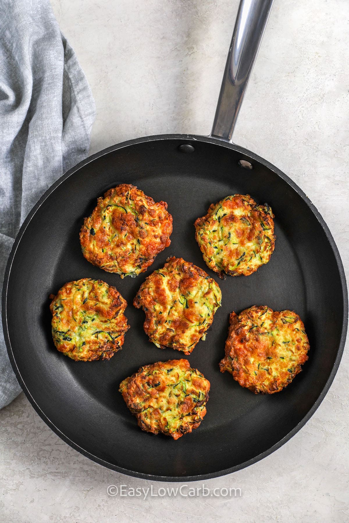 zucchini fritters being fried in a pan