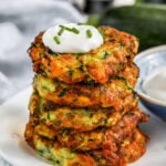 a stack of zucchini fritters topped with sour cream