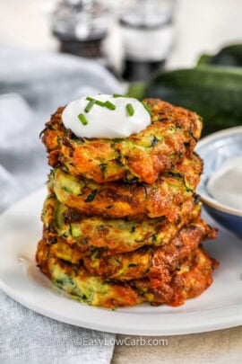 a stack of zucchini fritters topped with sour cream
