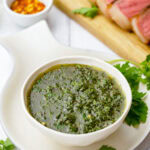 bowl of Easy Chimichurri Sauce with steak in the background