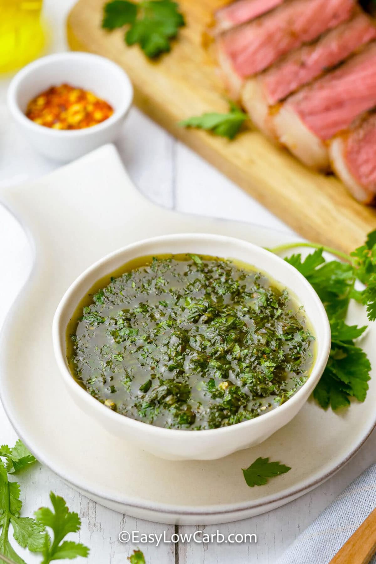 bowl of Easy Chimichurri Sauce with steak in the background