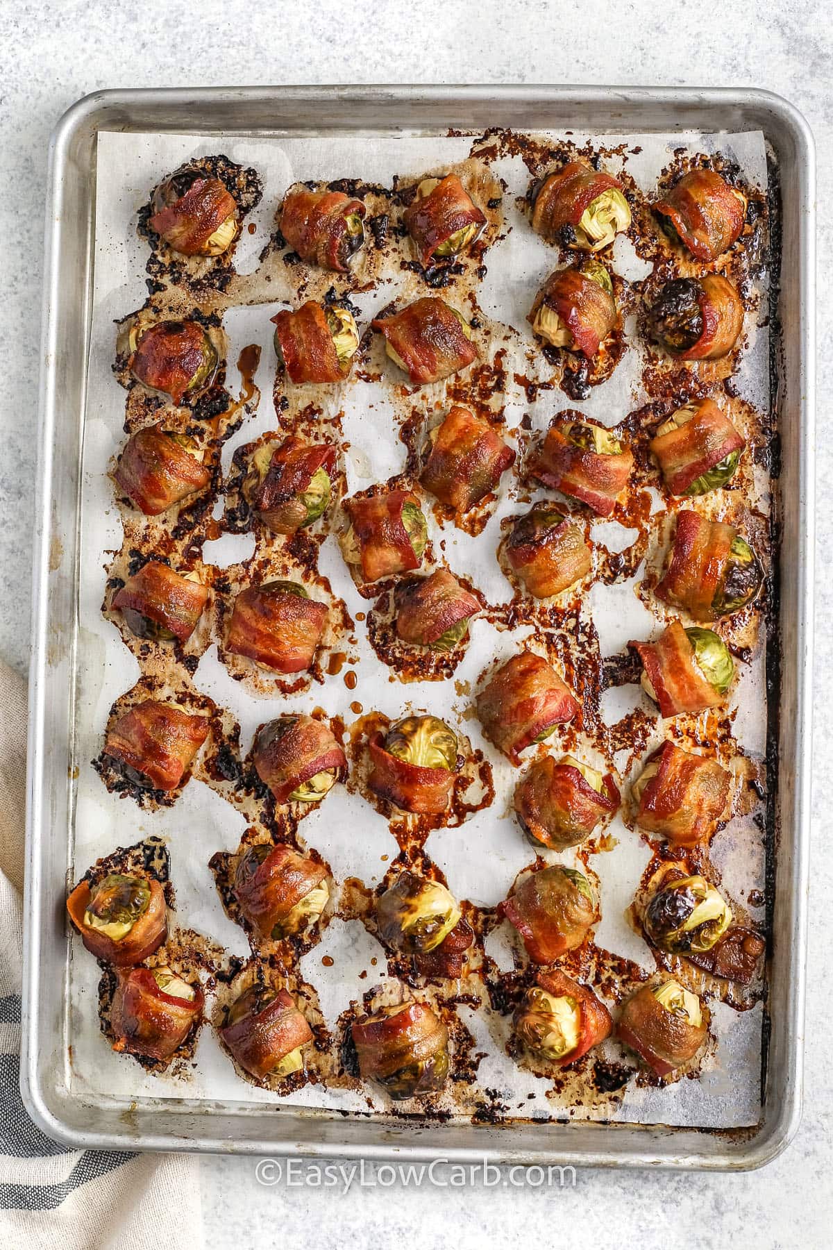 cooked bacon wrapped brussel sprouts on a tray with parchment