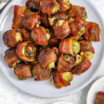 plate of bacon wrapped brussel sprouts, with two small serving plates