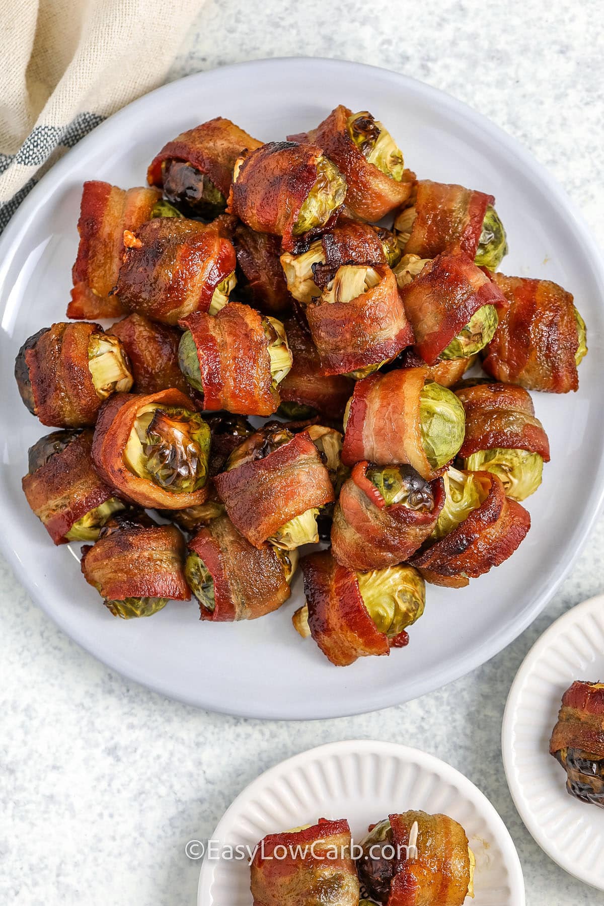 plate of bacon wrapped brussel sprouts, with two small serving plates