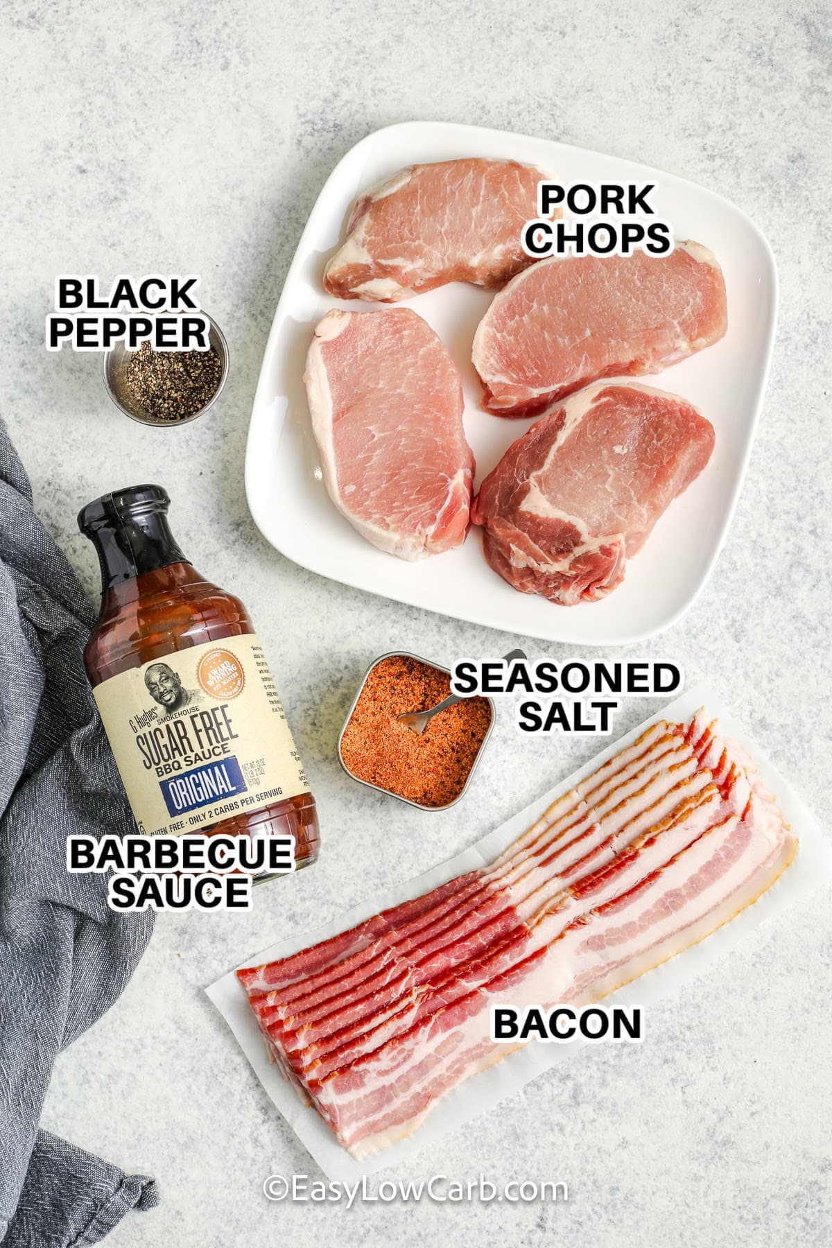 Ingredients to make bacon wrapped pork chops labeled: black pepper, pork chops, barbecue sauce, seasoned salt, and bacon