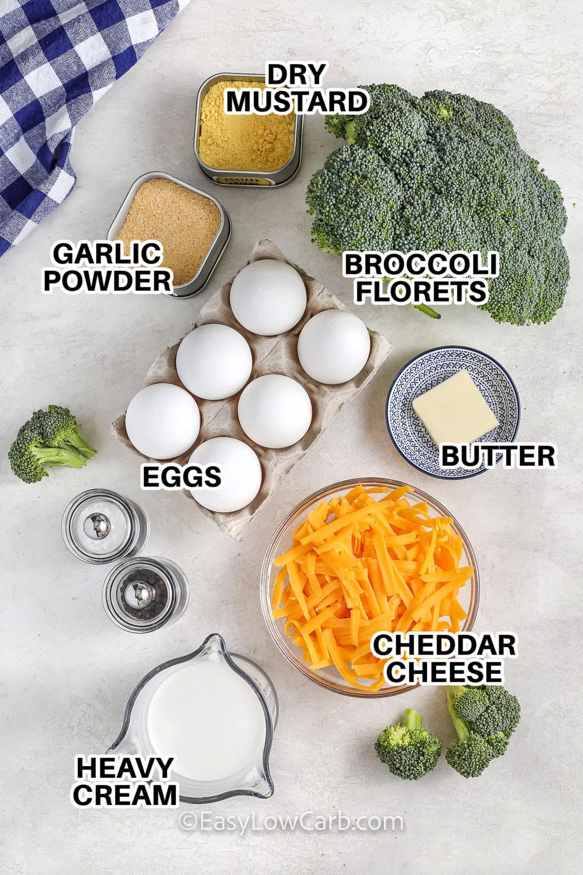 Ingredients to make a Broccoli Cheese Quiche labeled: dry mustard, garlic powder, broccoli florets, eggs, butter, heavy cream, and cheddar cheese