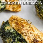 Spinach stuffed chicken breasts cooked on a baking tray with a title