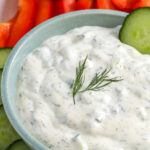 cucumber dip in a bowl surrounded by vegetables