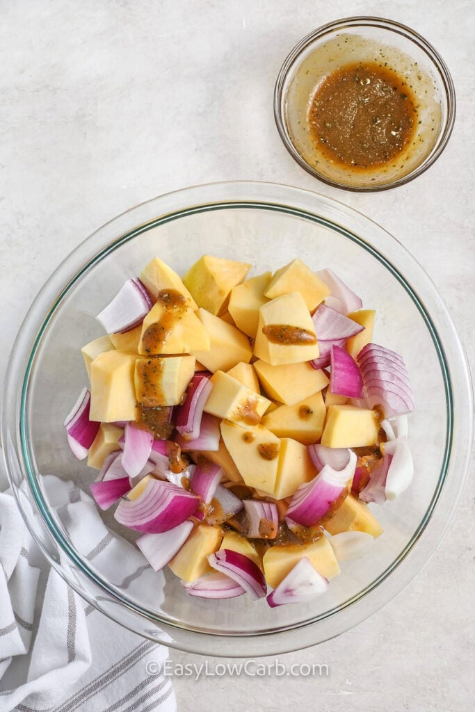 adding sauce to turnips and onions to make Sheet Pan Sausage and Vegetables