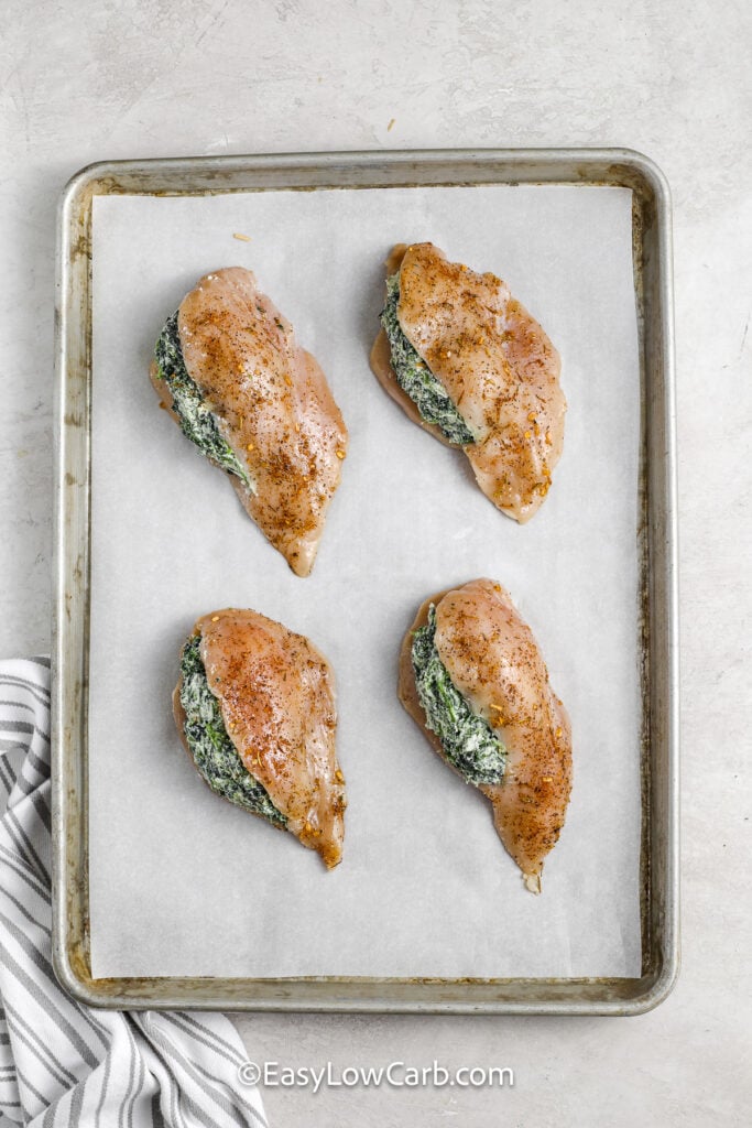 spinach stuffed chicken breasts prepared on a baking sheet