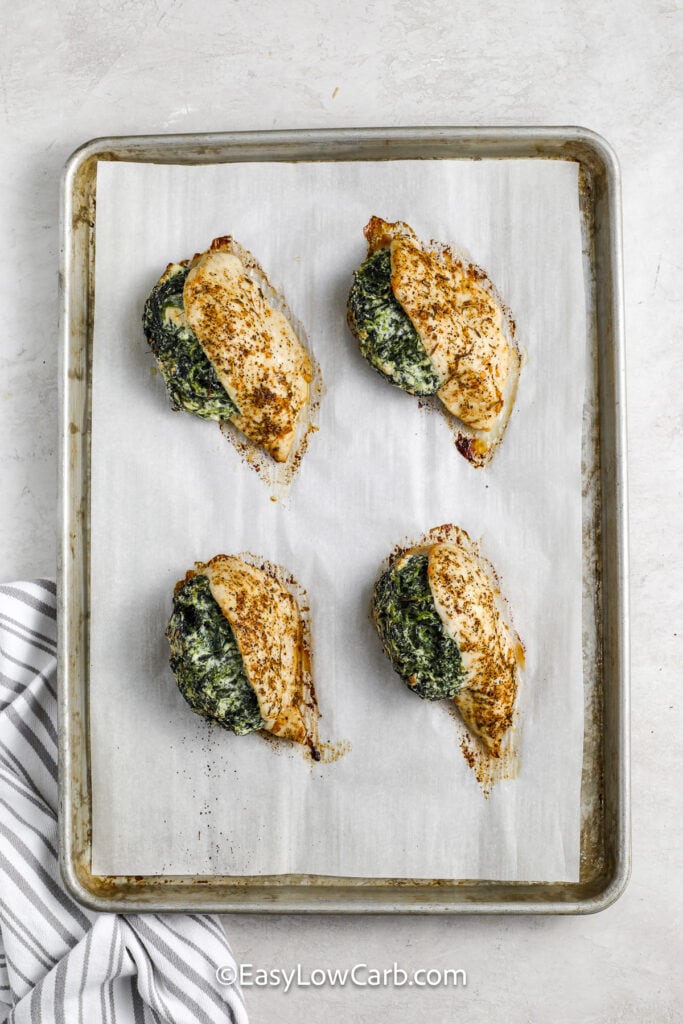 baked spinach stuffed chicken breasts on a baking tray