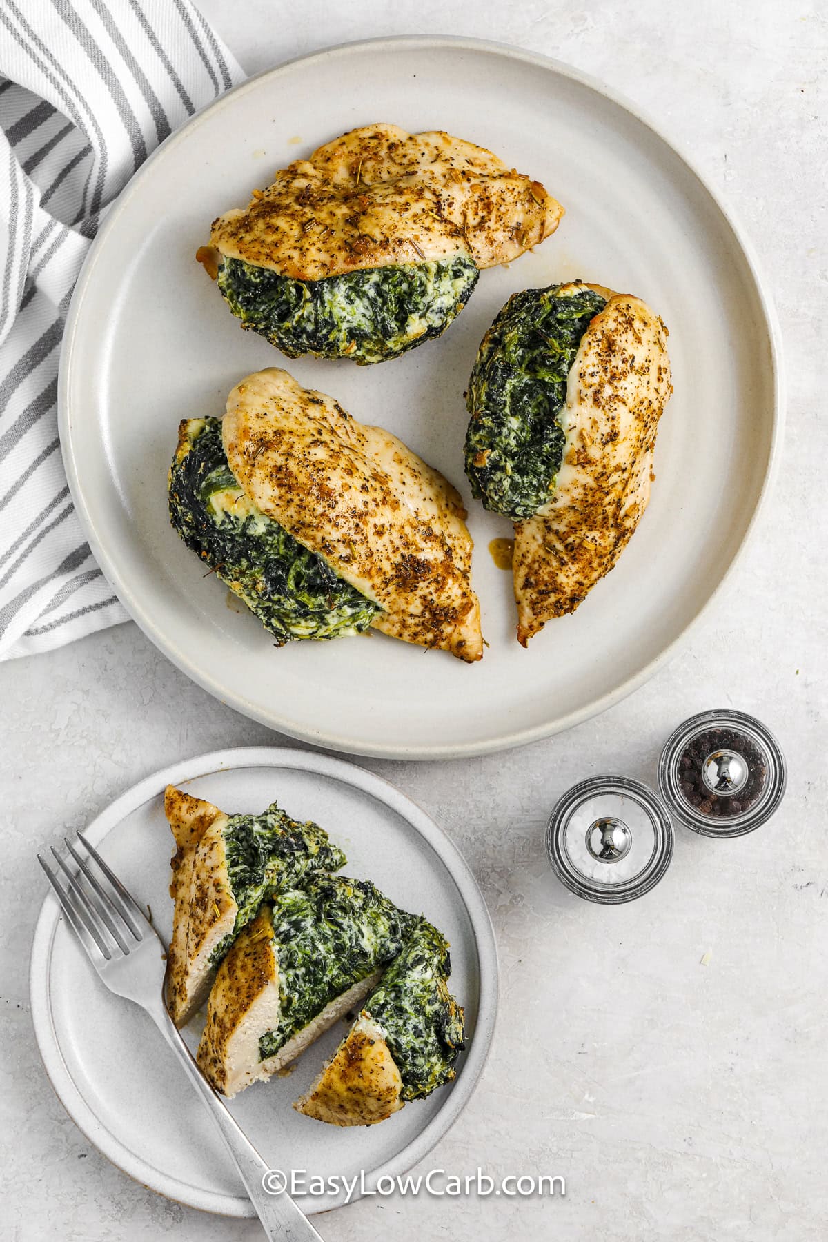 A serving dish with spinach stuffed chicken breasts and a chicken breast sliced on the side