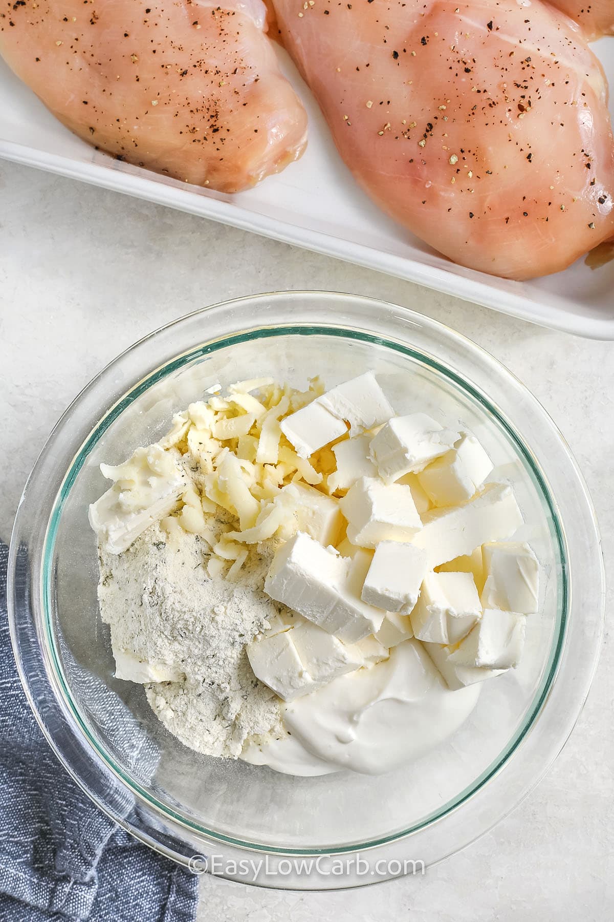 adding cheese , sour cream and seasonings together to make Baked Ranch Chicken