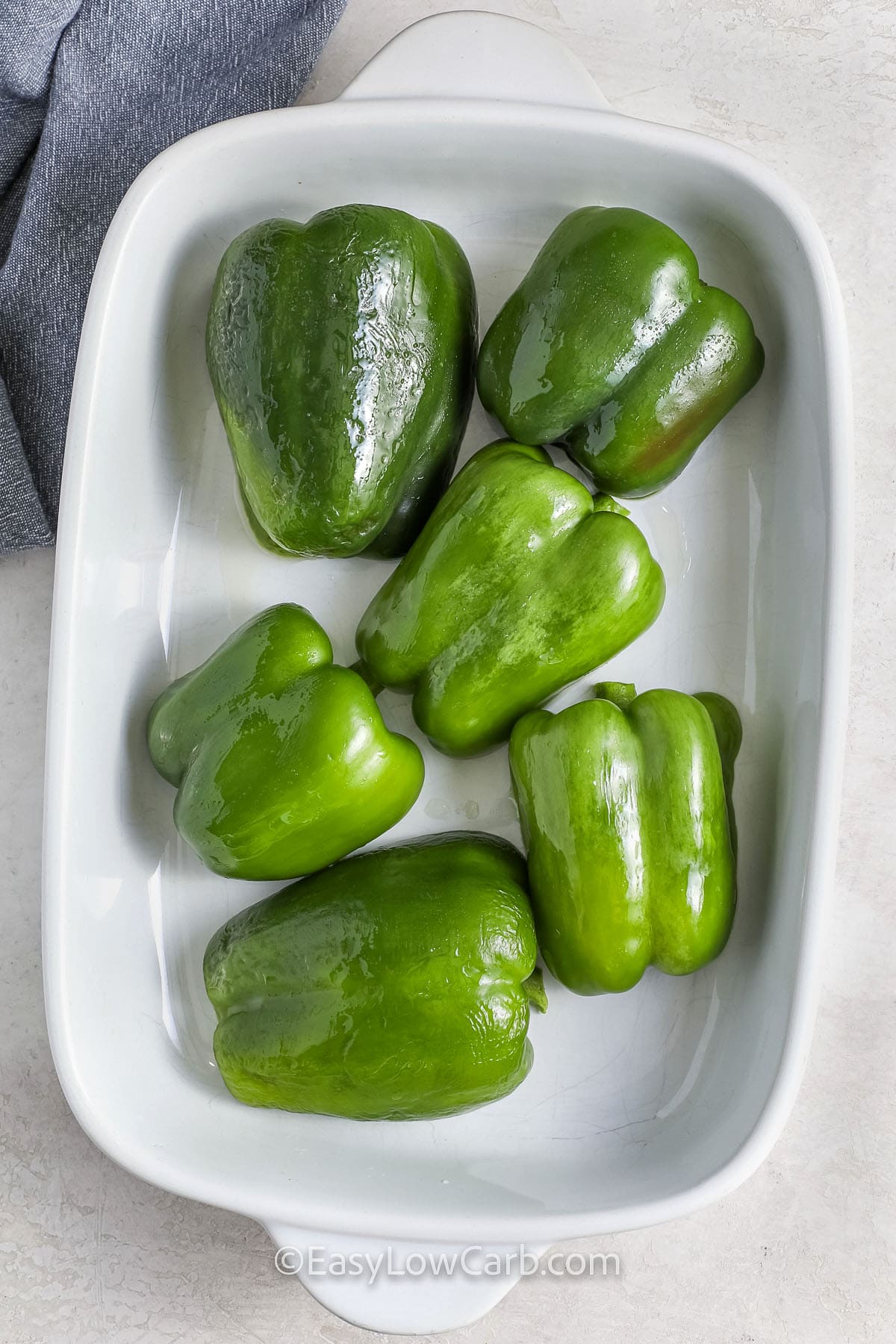 green bell peppers for cheesesteak stuffed peppers, halved in a baking pan, ready to cook