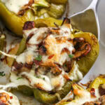 serving cheesesteak stuffed peppers from a baking dish