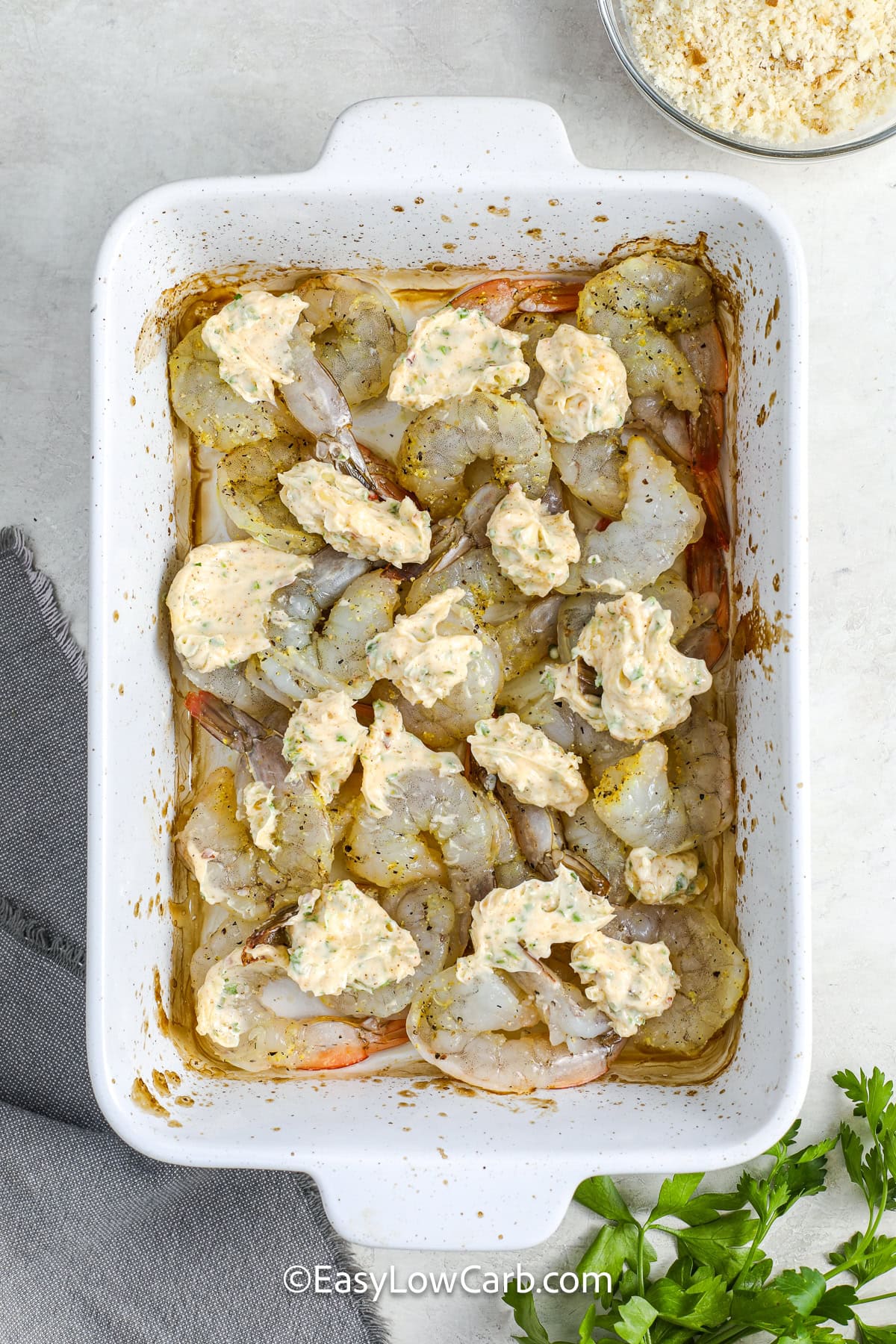 jumbo shrimp in a casserole dish with dollops of the butter mixture on top