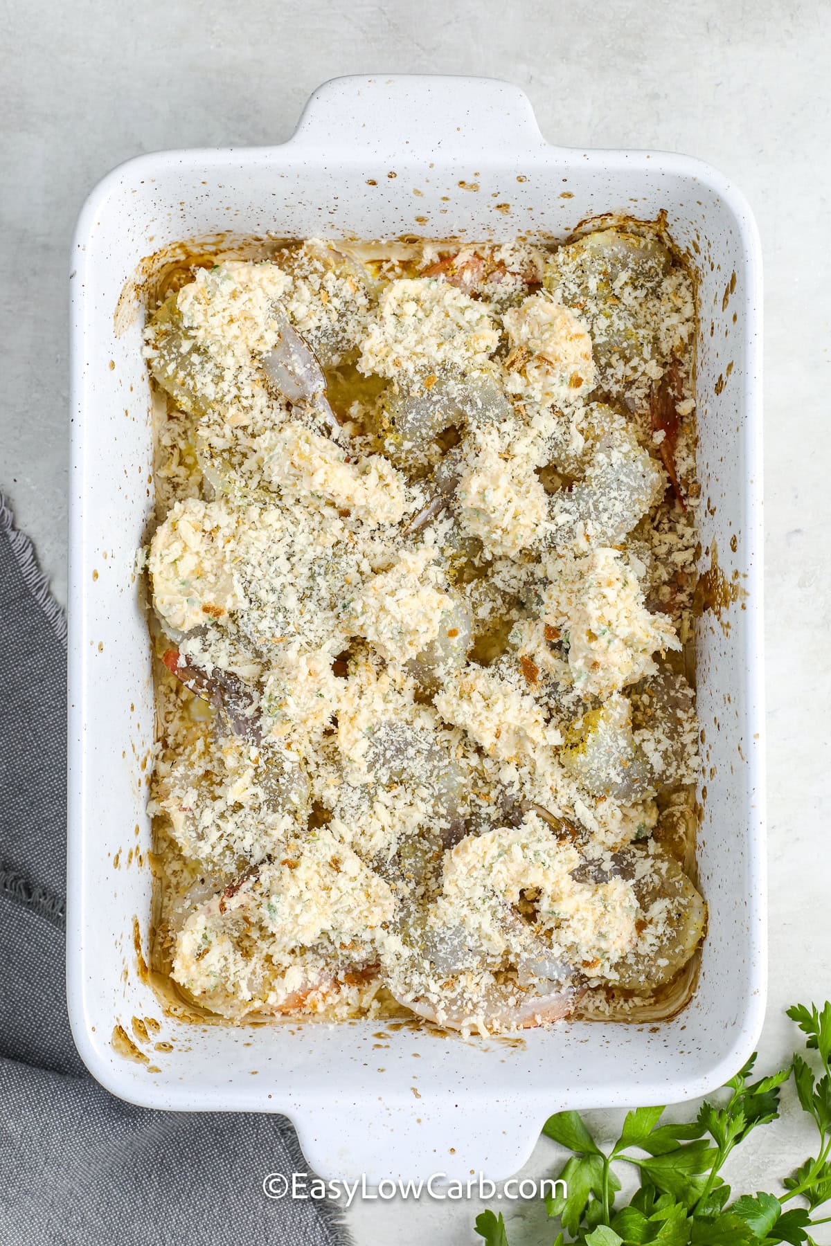 jumbo shrimp in a casserole dish with dollops of the butter mixture and panko bread crumbs on top