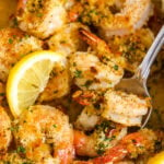 Baked shrimp scampi with lemon slices being served with a spoon