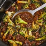 A pot of slow cooker beef and broccoli with a spoon scooping out a portion.