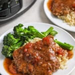 two plates of slow cooker cube steak served with cauliflower rice and broccoli