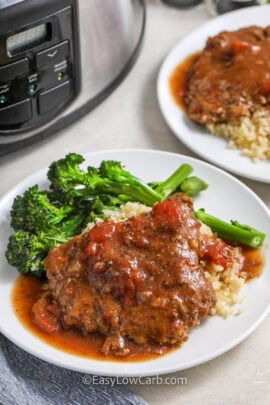 two plates of slow cooker cube steak served with cauliflower rice and broccoli