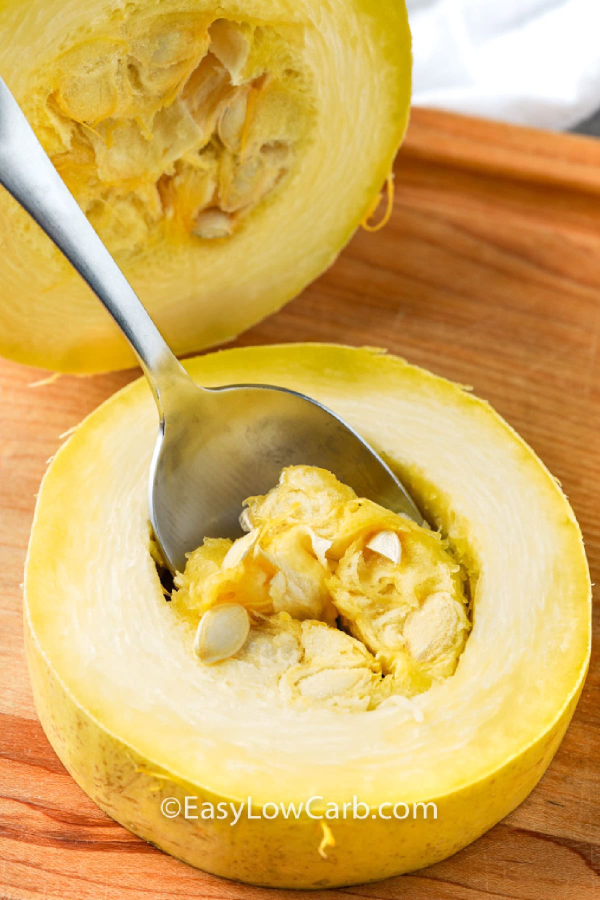 spoon scooping seeds from a spaghetti squash