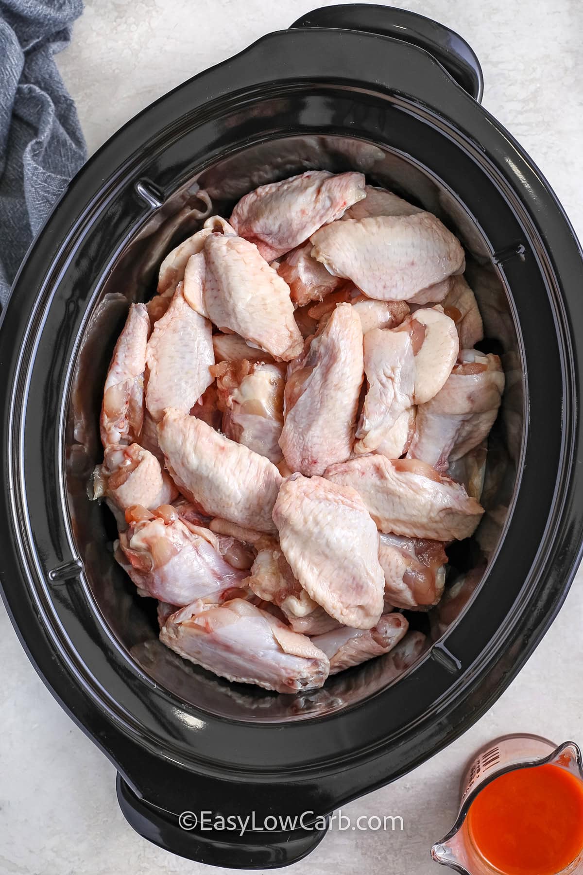 adding chicken to the pot to make Crockpot Chicken Wings