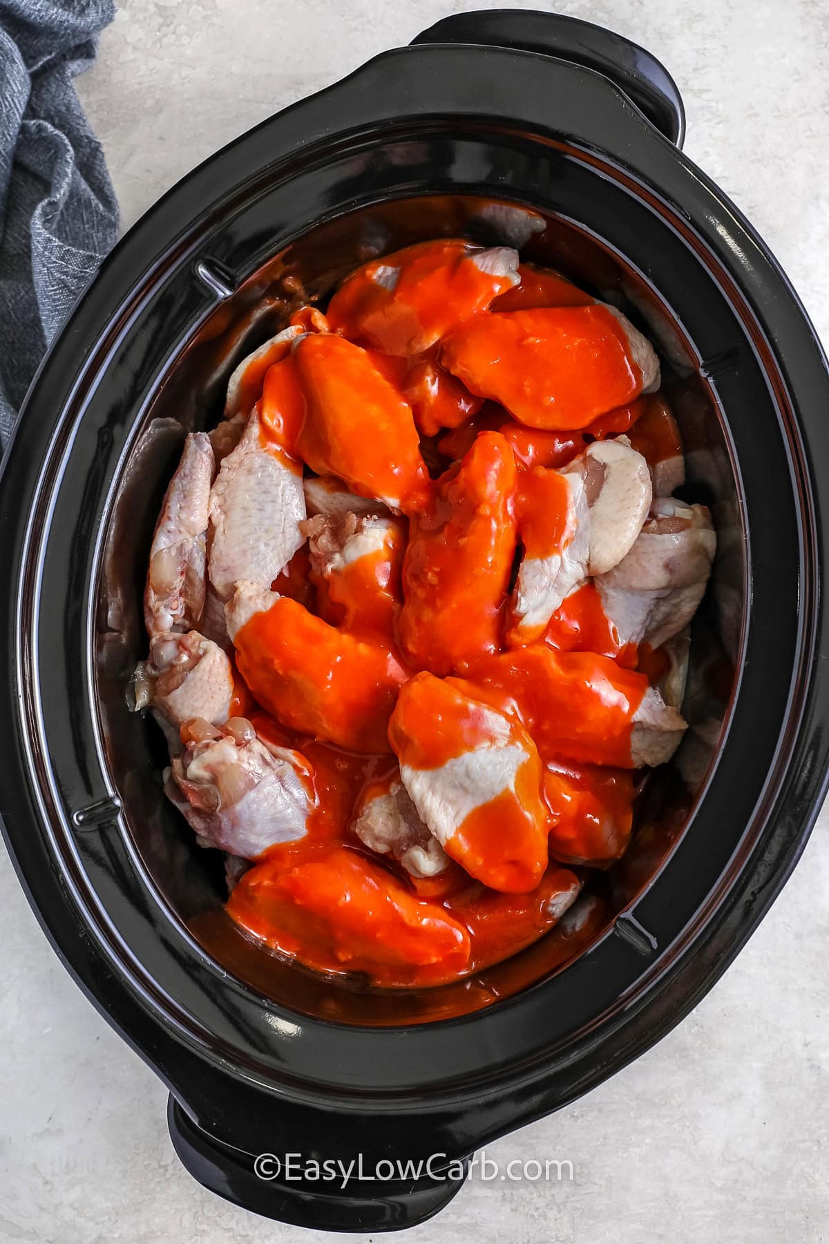 adding sauce and chicken to the crockpot to make Crockpot Chicken Wings