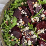 roasted beet salad in a bowl with salt and pepper on the side, with a title