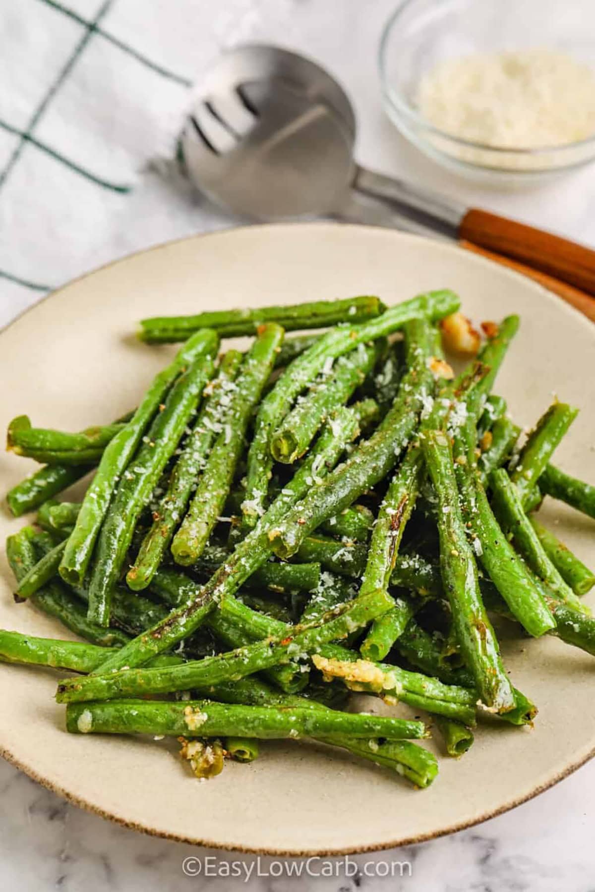 Oven roasted green beans with parmesan offers a delightful combination of crispy and tender textures. Coated in olive oil, garlic, and parmesan cheese, the beans develop a golden, slightly crispy exterior while remaining firm and flavorful inside. This quick and easy recipe is a great way to add variety to your vegetable side dishes. It’s a nutritious, simple dish that works well with any main course. #easylowcarb plated Oven Roasted Green Beans