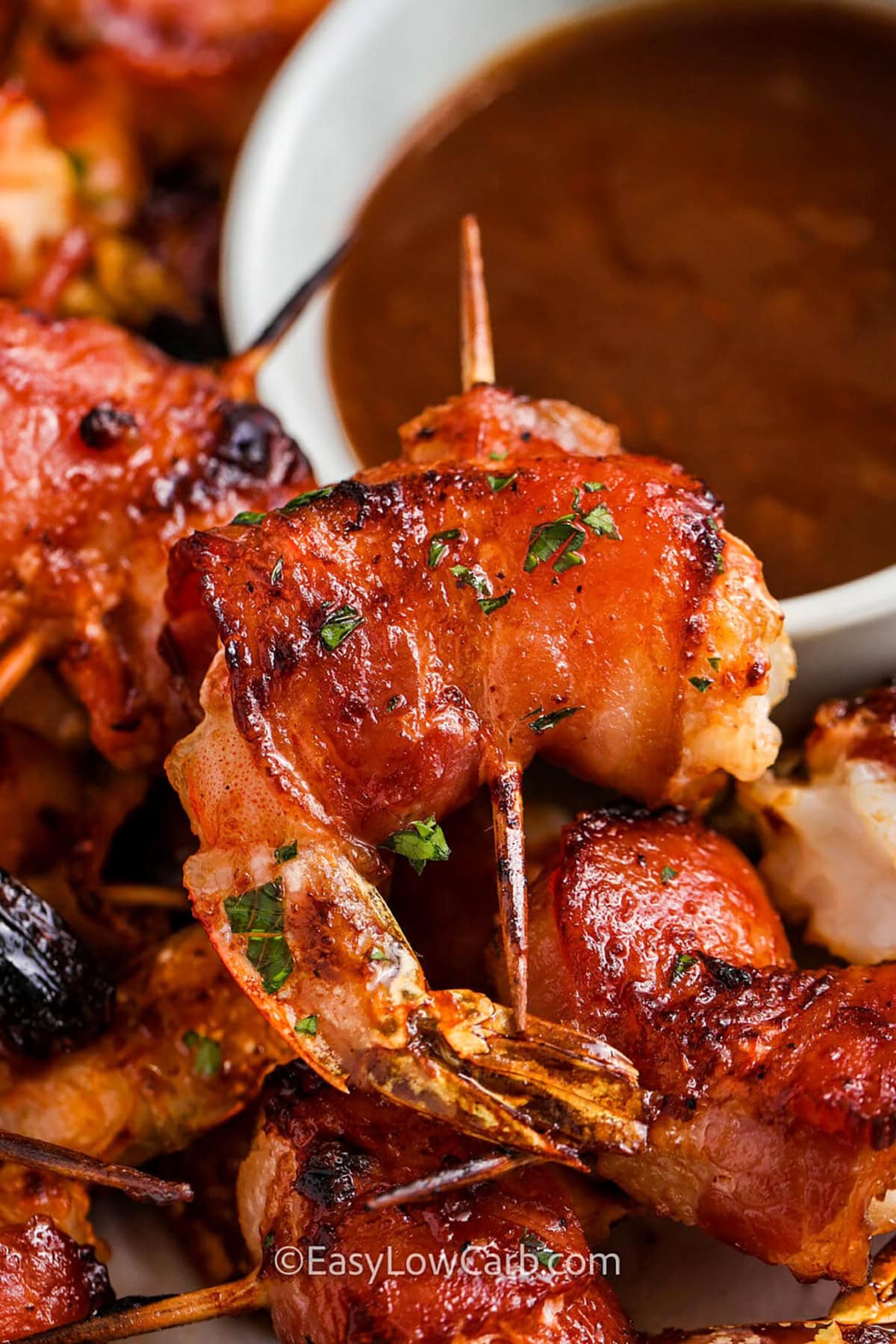 This bacon-wrapped shrimp recipe takes your shrimp to the next level with a combination of crispy, smoky bacon and tender, sweet shrimp. This easy-to-make recipe is perfect for those who love flavorful, quick meals that are sure to impress. The smoky bacon complements the delicate shrimp, making every bite a perfect blend of flavors. Whether served as an appetizer or a main course, this dish is a hit every time! #easylowcarb juicy Bacon Wrapped Shrimp Recipe with dip on a plate