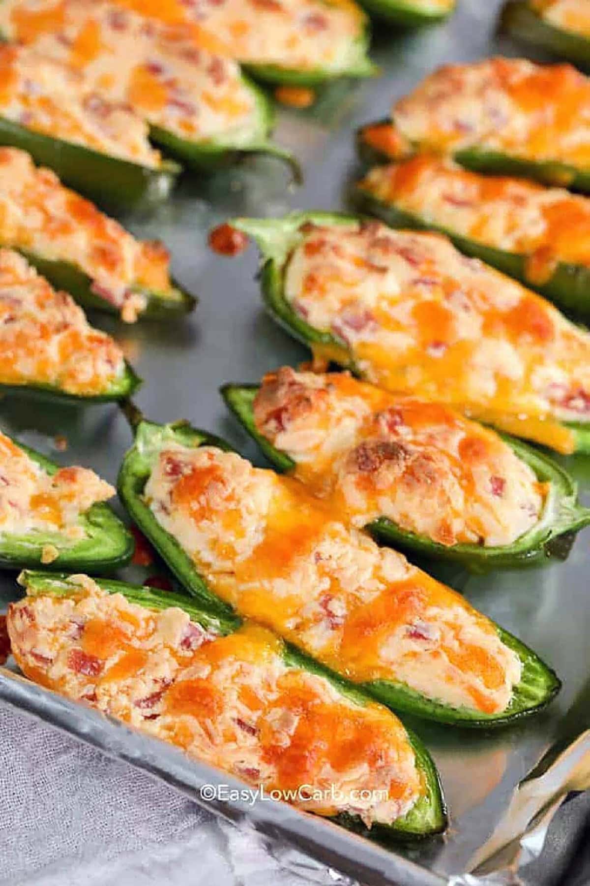 You can't go wrong with these jalapeno poppers! The creamy cream cheese filling, mixed with sharp cheddar and crispy bacon, gives the perfect balance of flavor. Plus, baking them ensures the cheese melts into a gooey, golden topping. It’s a deliciously spicy treat that's easy to make and always disappears fast at parties. A crowd-pleasing favorite! #easylowcarb Baked Jalapeno Poppers on a sheet pan