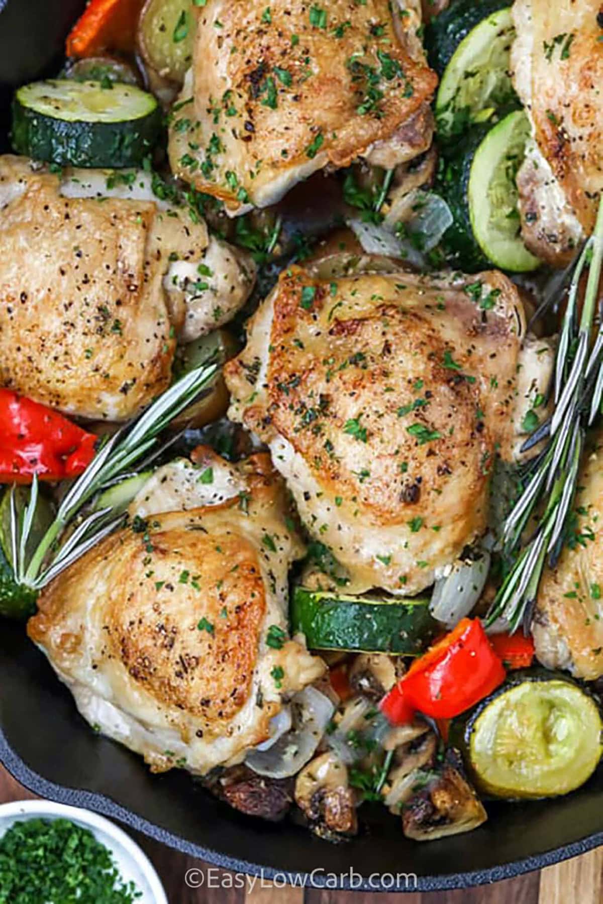 For a low carb, flavorful dinner, try this lemon rosemary chicken! Coated in a crispy garlic and paprika crust, the chicken is infused with fresh rosemary and a tangy lemon sauce that takes the flavor to the next level. Whether you use thighs or breasts, bake it in the oven and pair it with roasted veggies for an easy, delicious meal! #easylowcarb Lemon Rosemary Chicken with peppers and zucchini in a pan