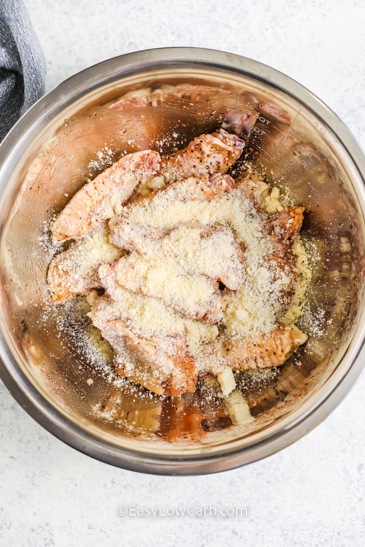 parmesan added to chicken wings in a bowl